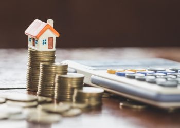 House model on top of stack of money as growth of mortgage credit, Concept of property management. Invesment and Risk Management.